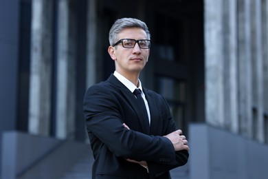 Photo of International relations. Diplomat with crossed arms in suit outdoors