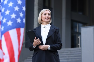 International relations. Diplomat with clipboard near flag of USA outdoors