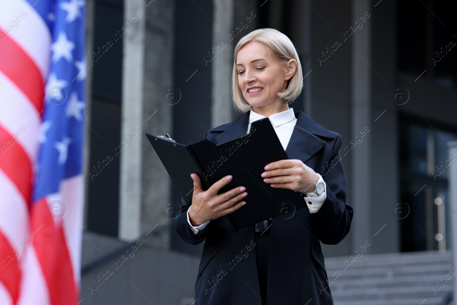 Photo of International relations. Diplomat with clipboard near flag of USA outdoors