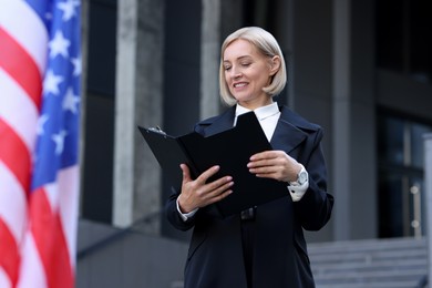 International relations. Diplomat with clipboard near flag of USA outdoors