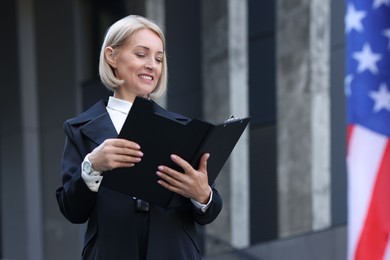 Photo of International relations. Diplomat with clipboard near flag of USA outdoors