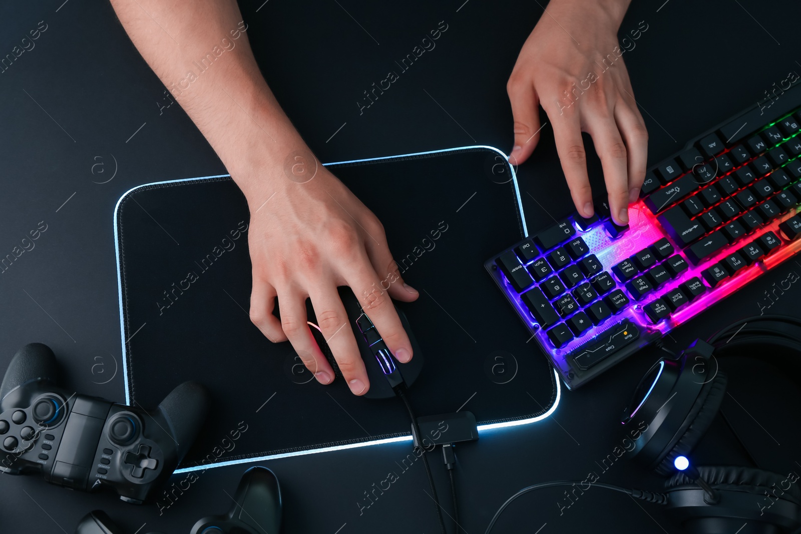 Photo of Gamer using modern wired computer mouse at black table, top view