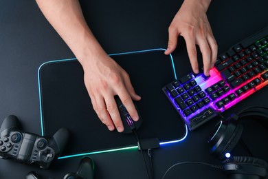 Photo of Gamer using modern wired computer mouse at black table, top view