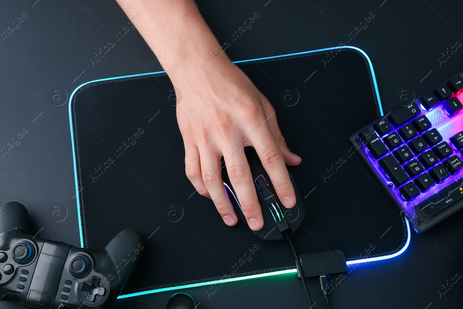 Photo of Gamer using modern wired computer mouse at black table, top view