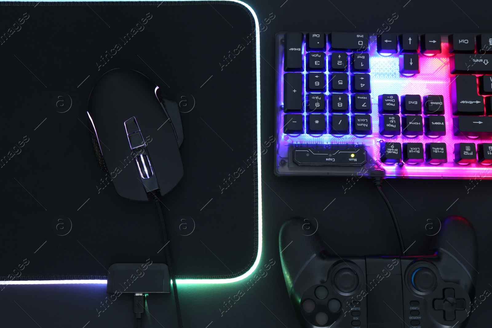 Photo of Computer mouse, RGB keyboard and game controller on black background, flat lay