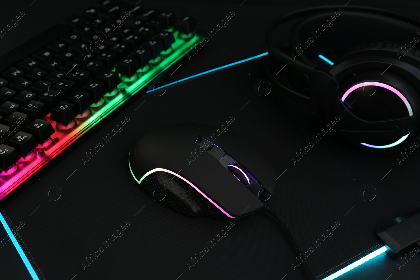 Photo of Computer mouse, RGB keyboard and headset on black background, closeup