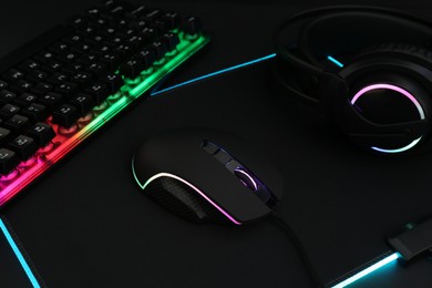 Photo of Computer mouse, RGB keyboard and headset on black background, closeup