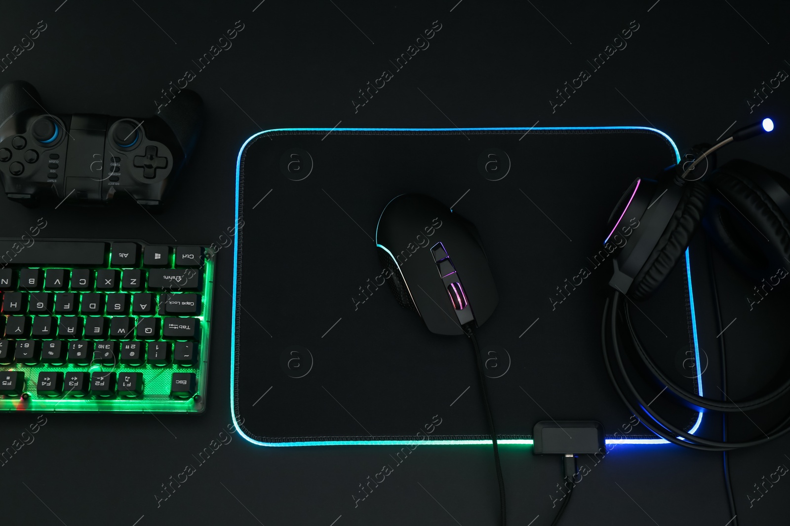 Photo of Computer mouse, headset, RGB keyboard and game controller on black background, flat lay