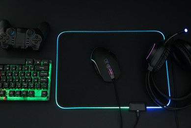 Photo of Computer mouse, headset, RGB keyboard and game controller on black background, flat lay