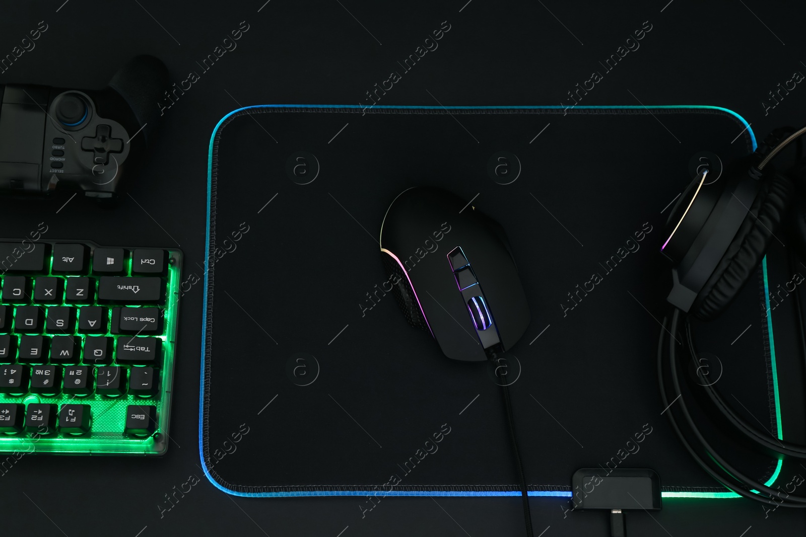 Photo of Computer mouse, headset, RGB keyboard and game controller on black background, flat lay