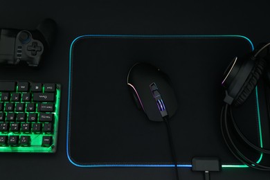 Photo of Computer mouse, headset, RGB keyboard and game controller on black background, flat lay