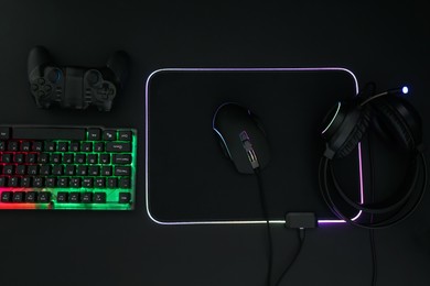 Photo of Computer mouse, headset, RGB keyboard and game controller on black background, flat lay