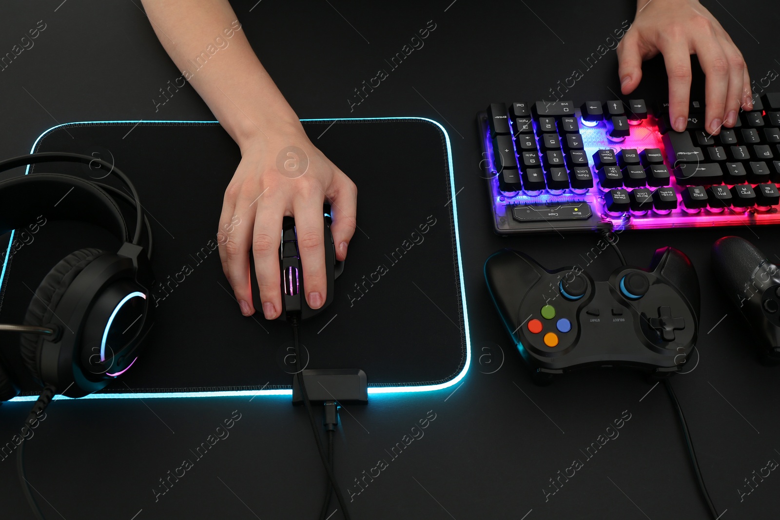 Photo of Gamer using modern wired computer mouse at dark table, above view