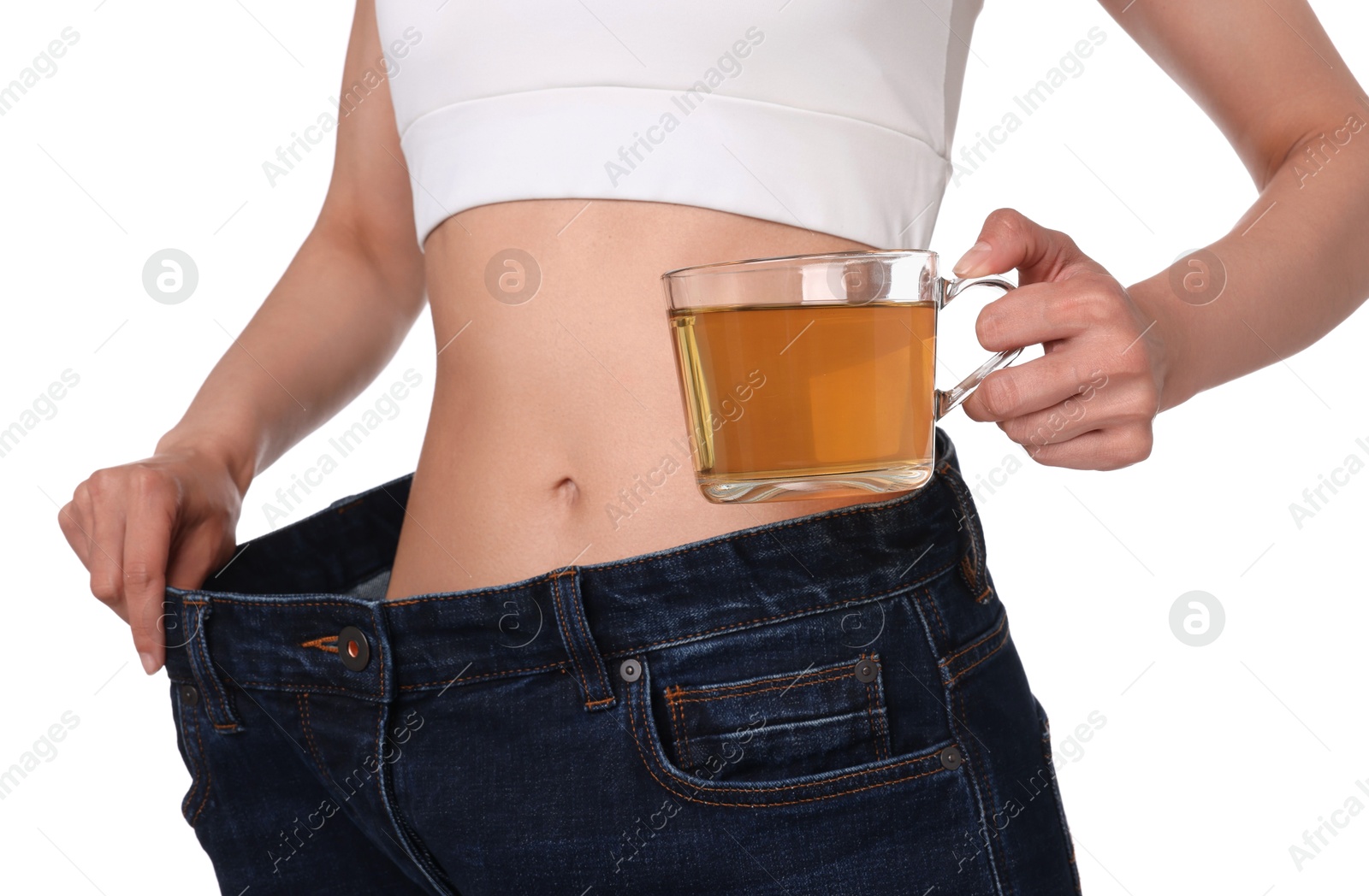 Photo of Weight loss concept. Woman with cup of diet tea and big pants on white background, closeup