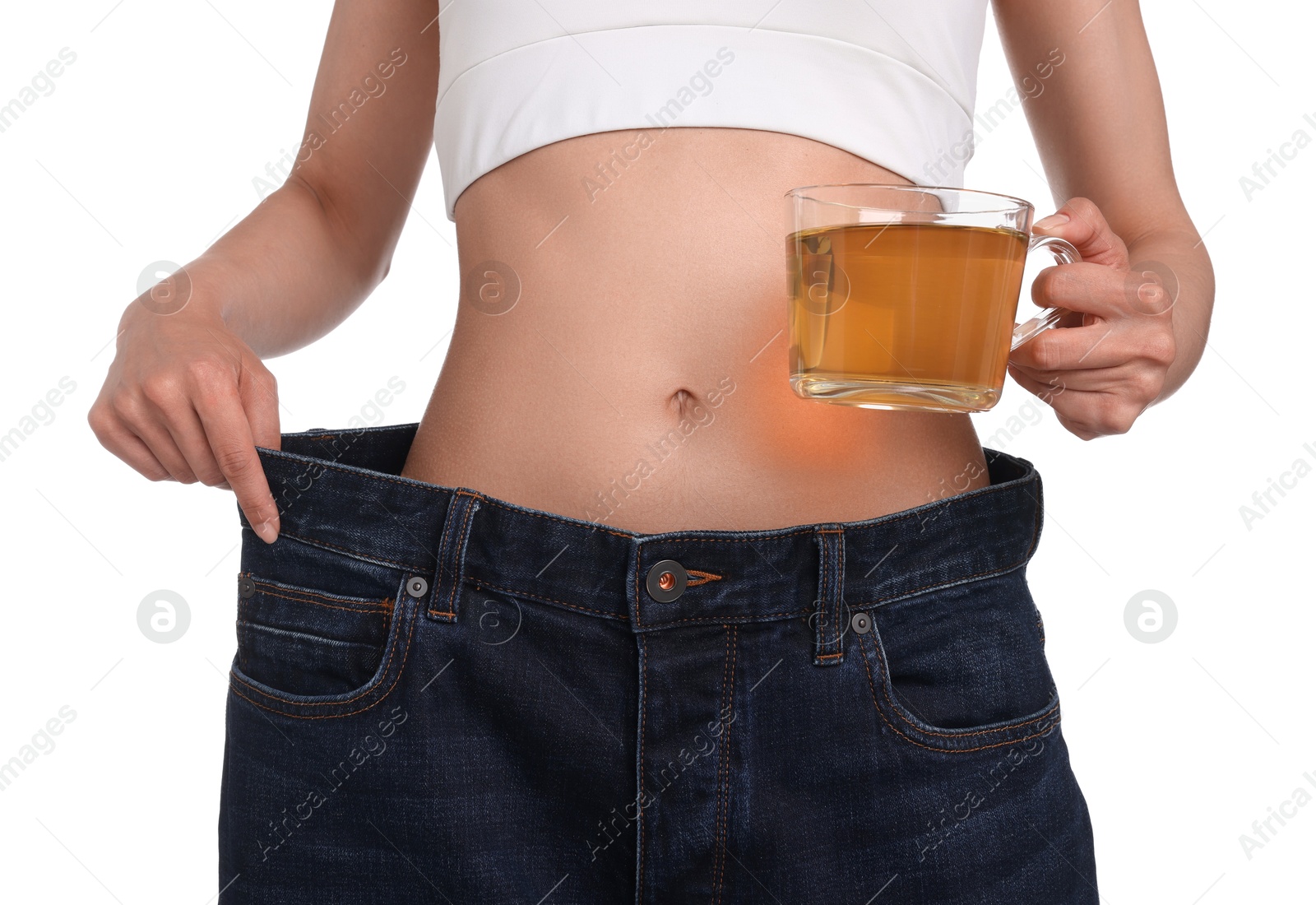 Photo of Weight loss concept. Woman with cup of diet tea and big pants on white background, closeup