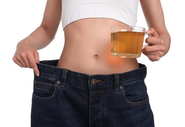 Photo of Weight loss concept. Woman with cup of diet tea and big pants on white background, closeup