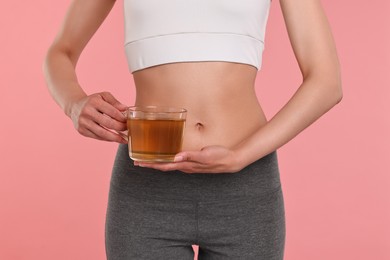 Photo of Weight loss concept. Woman with cup of diet tea on pink background, closeup