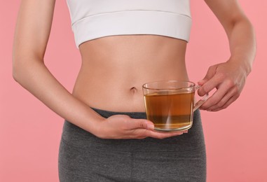 Photo of Weight loss concept. Woman with cup of diet tea on pink background, closeup