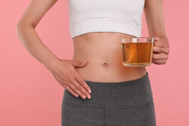 Weight loss concept. Woman with cup of diet tea on pink background, closeup