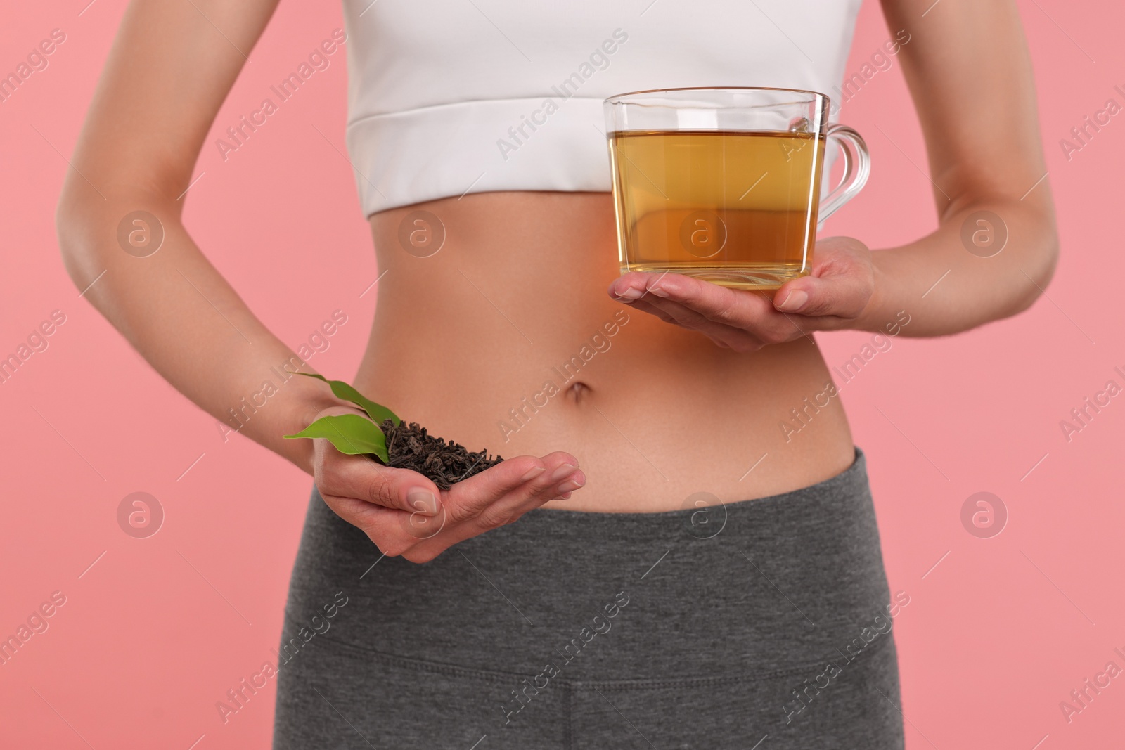 Photo of Weight loss concept. Woman with cup of diet tea and dry leaves on pink background, closeup