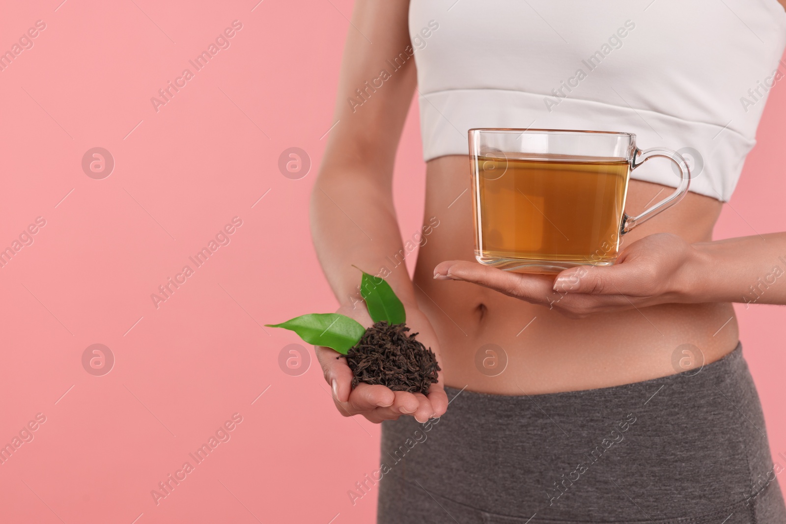 Photo of Weight loss concept. Woman with cup of diet tea and dry leaves on pink background, closeup