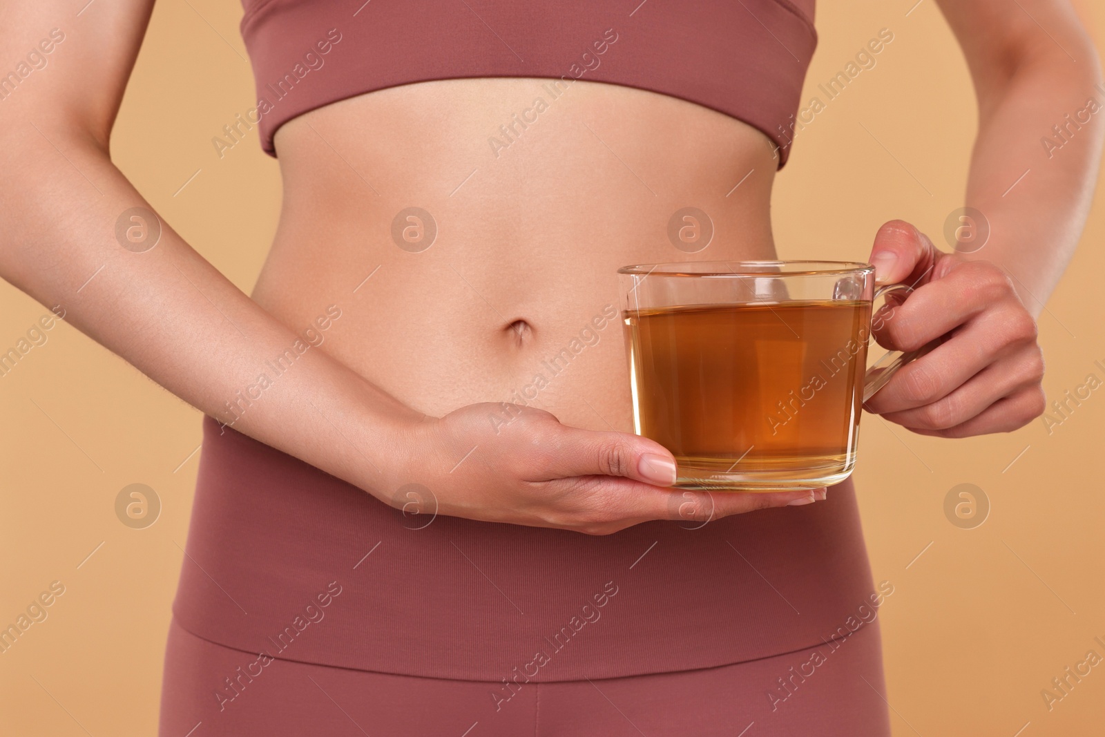 Photo of Weight loss concept. Woman with cup of diet tea on beige background, closeup