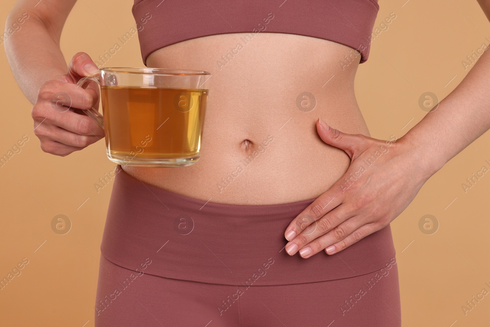 Photo of Weight loss concept. Woman with cup of diet tea on beige background, closeup