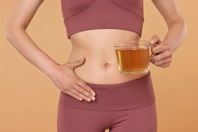 Photo of Weight loss concept. Woman with cup of diet tea on beige background, closeup