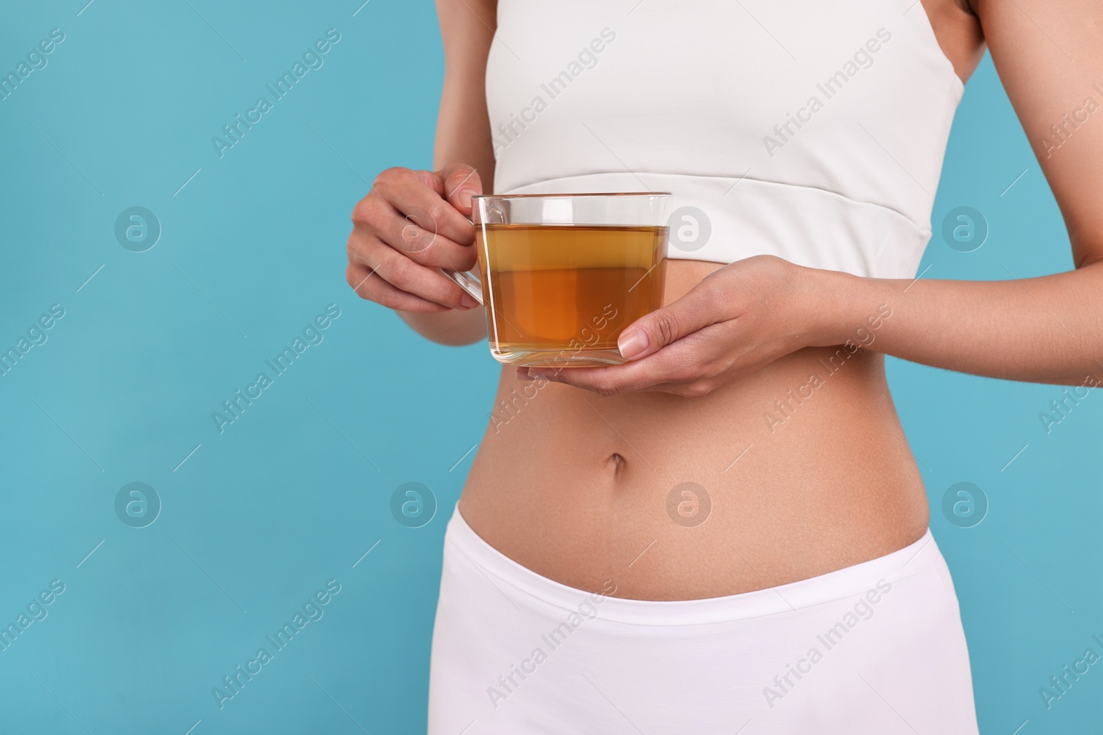 Photo of Weight loss concept. Woman with cup of diet tea on light blue background, closeup