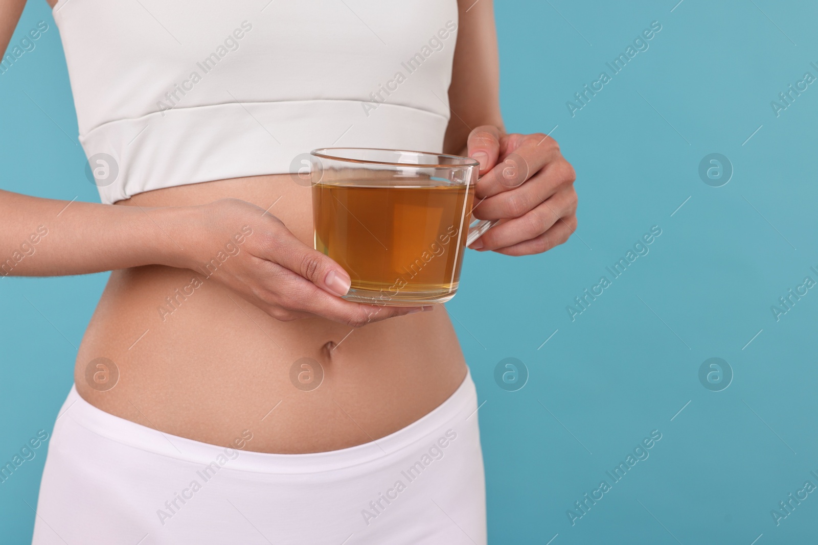 Photo of Weight loss concept. Woman with cup of diet tea on light blue background, closeup