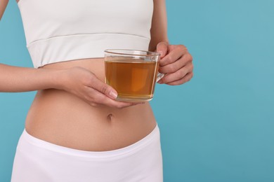 Photo of Weight loss concept. Woman with cup of diet tea on light blue background, closeup