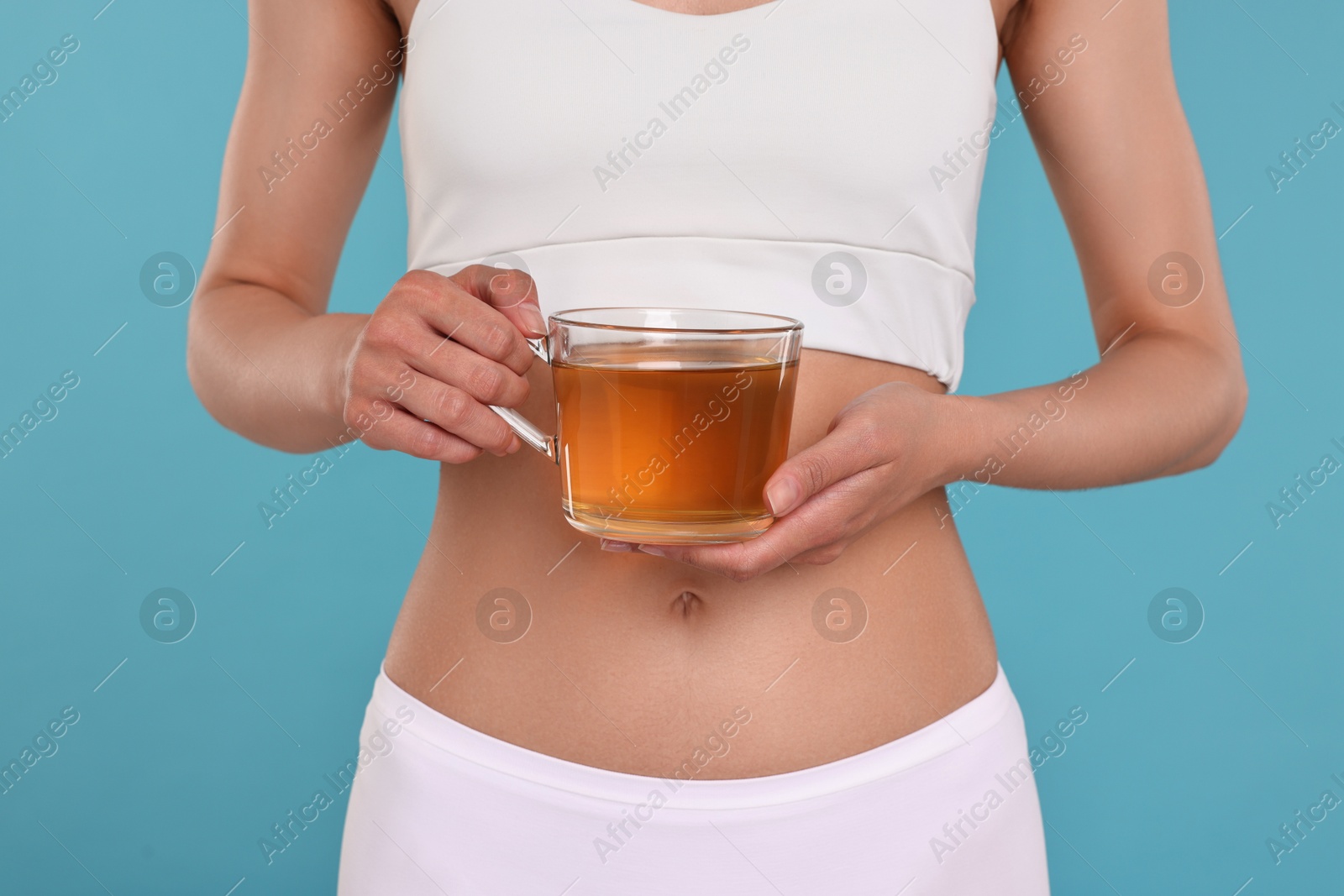 Photo of Weight loss concept. Woman with cup of diet tea on light blue background, closeup