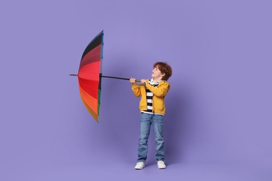 Photo of Little boy with rainbow umbrella on purple background