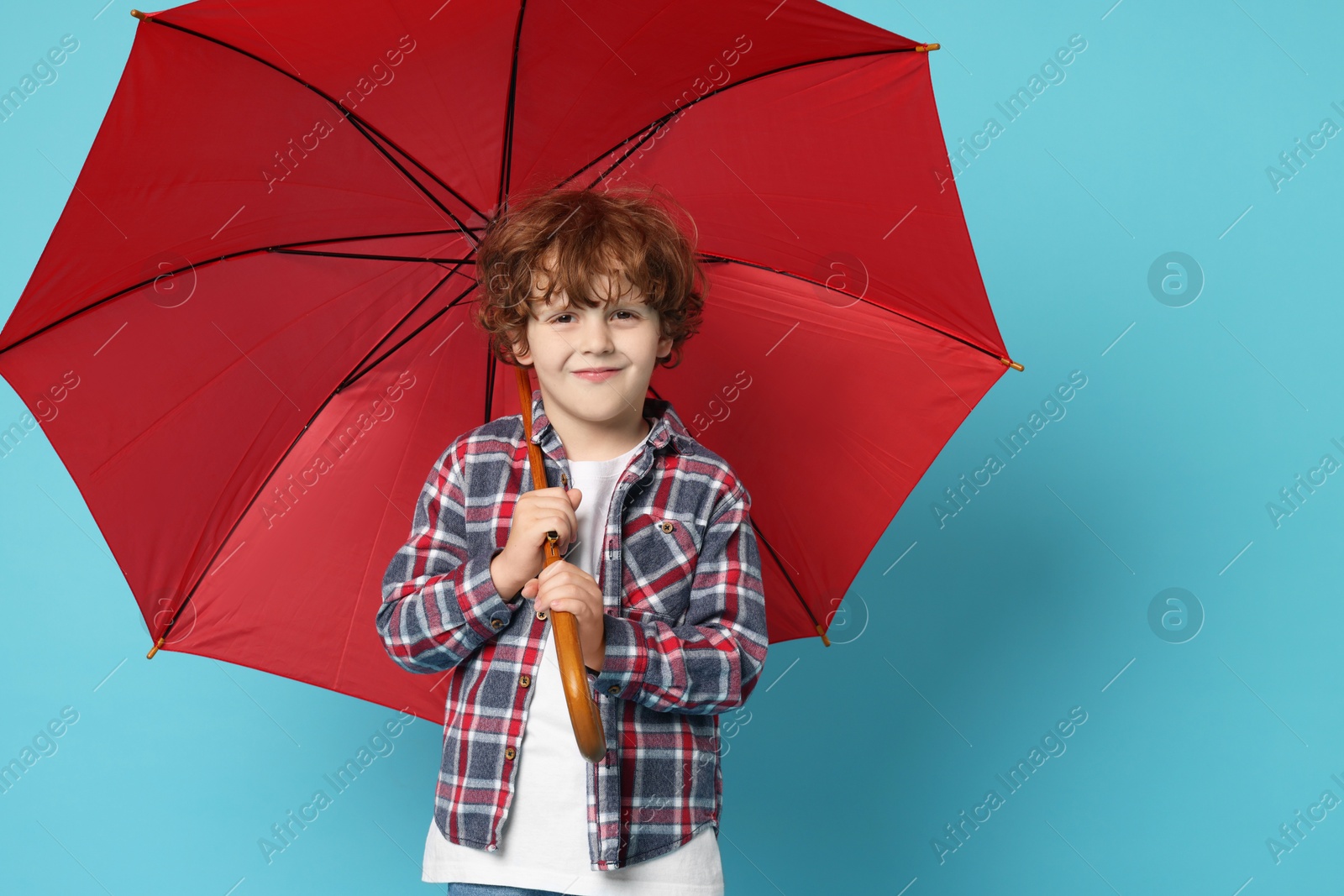 Photo of Little boy with red umbrella on light blue background