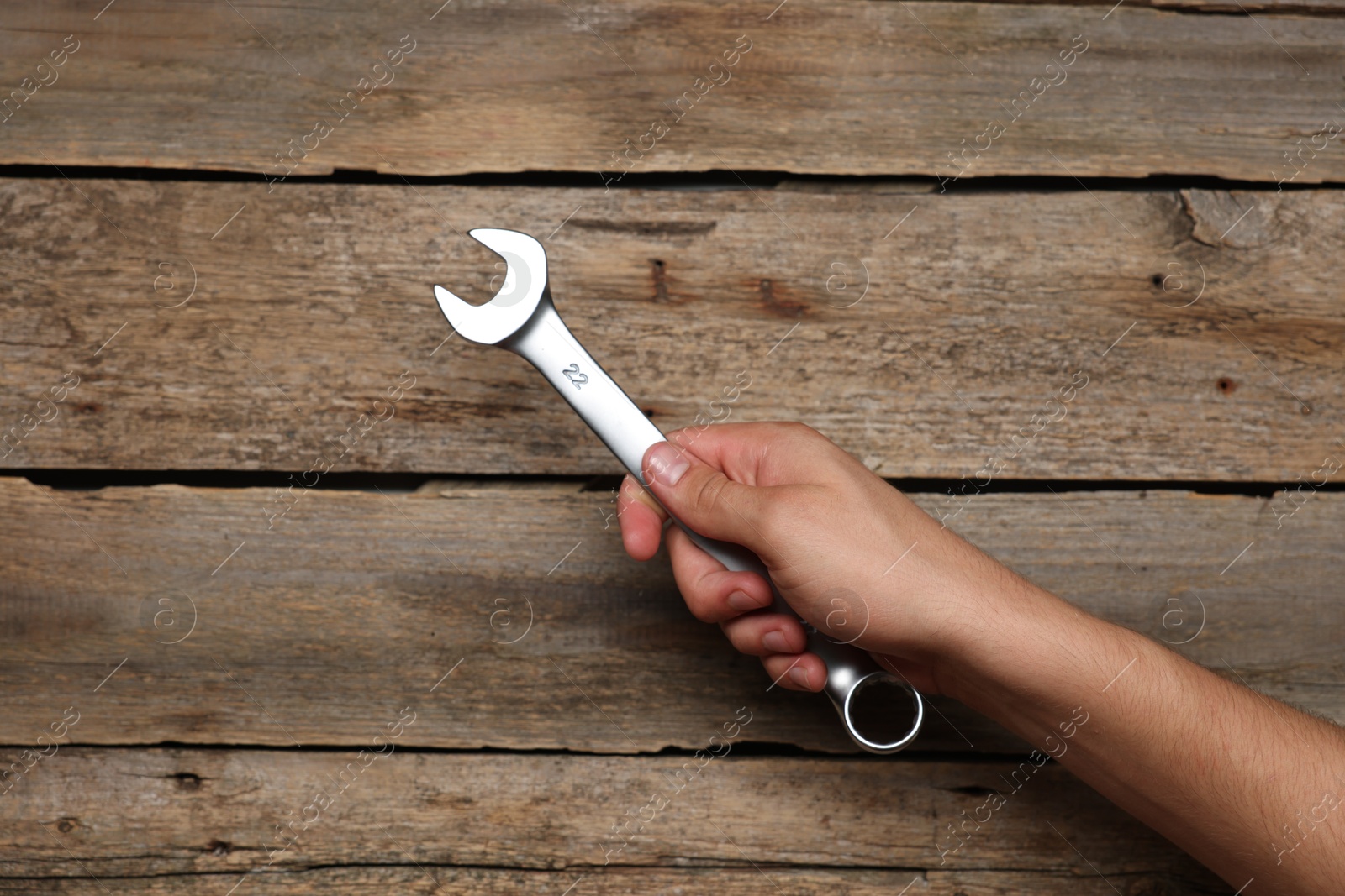 Photo of Auto mechanic with wrench at wooden table, closeup