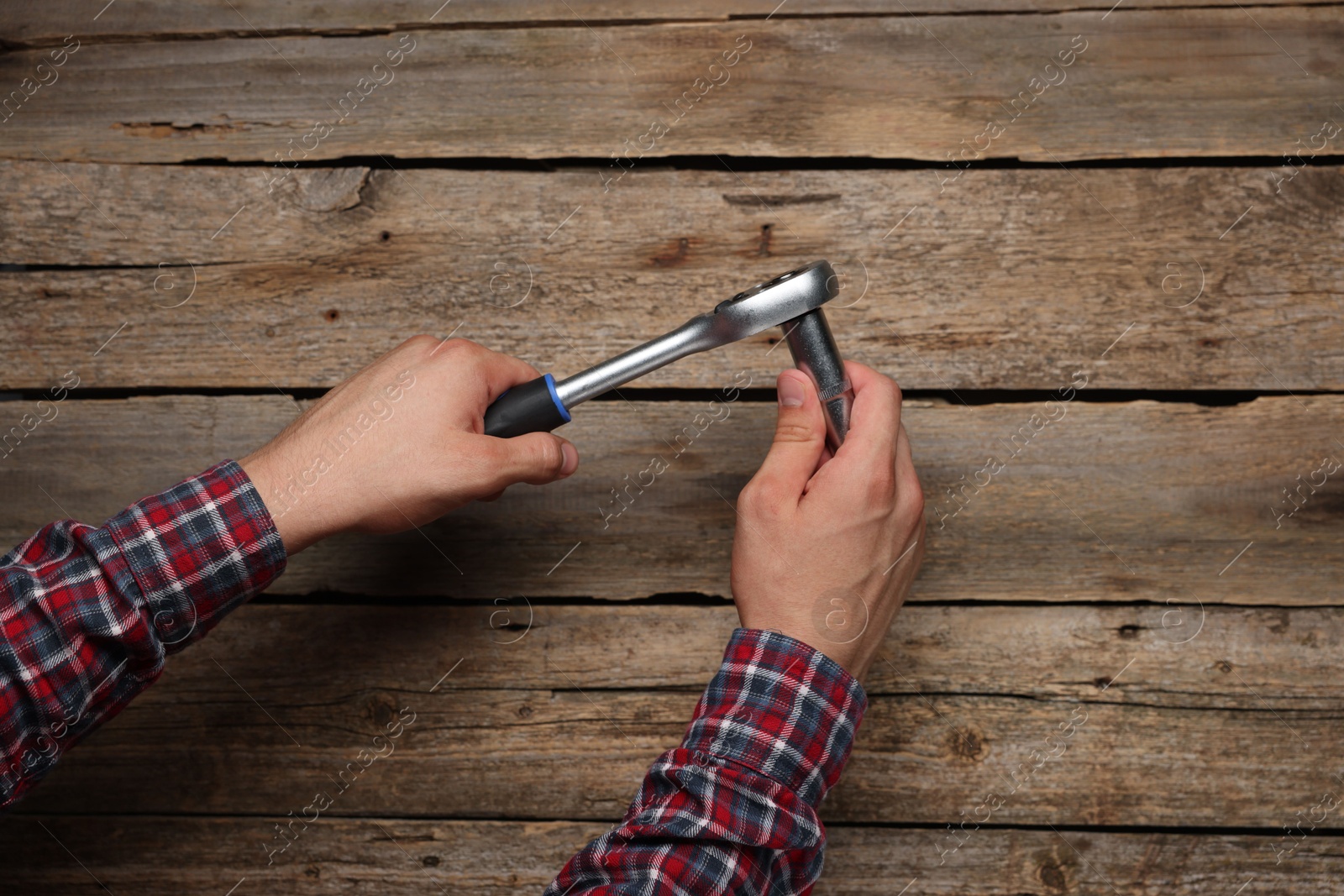 Photo of Auto mechanic with torque wrench at wooden table, closeup