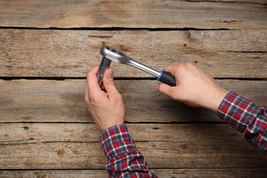 Photo of Auto mechanic with torque wrench at wooden table, closeup