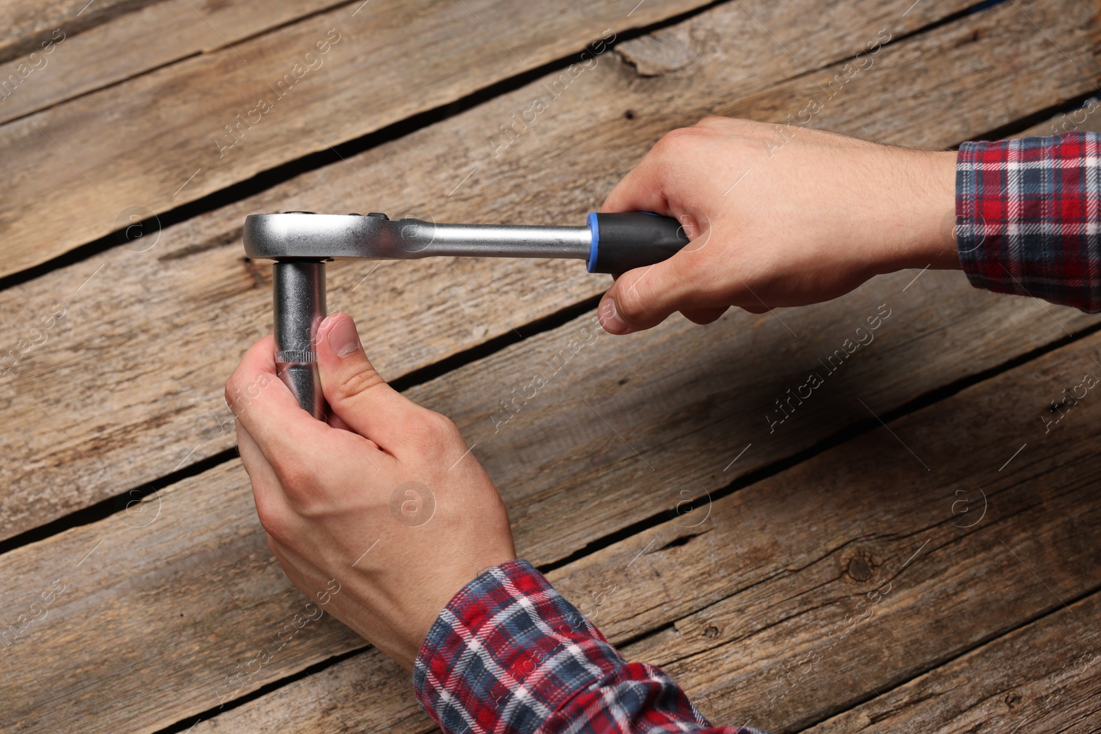 Photo of Auto mechanic with torque wrench at wooden table, closeup