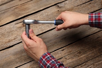 Auto mechanic with torque wrench at wooden table, closeup