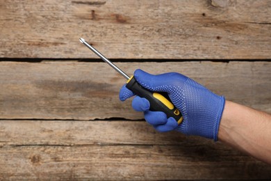 Photo of Auto mechanic with screwdriver at wooden table, closeup