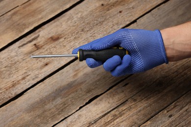 Photo of Auto mechanic with screwdriver at wooden table, closeup