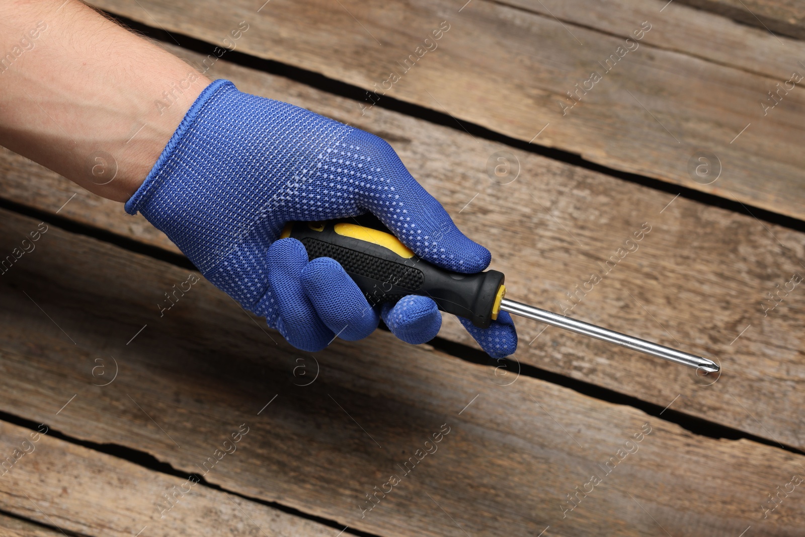 Photo of Auto mechanic with screwdriver at wooden table, closeup