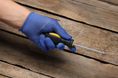 Photo of Auto mechanic with screwdriver at wooden table, closeup