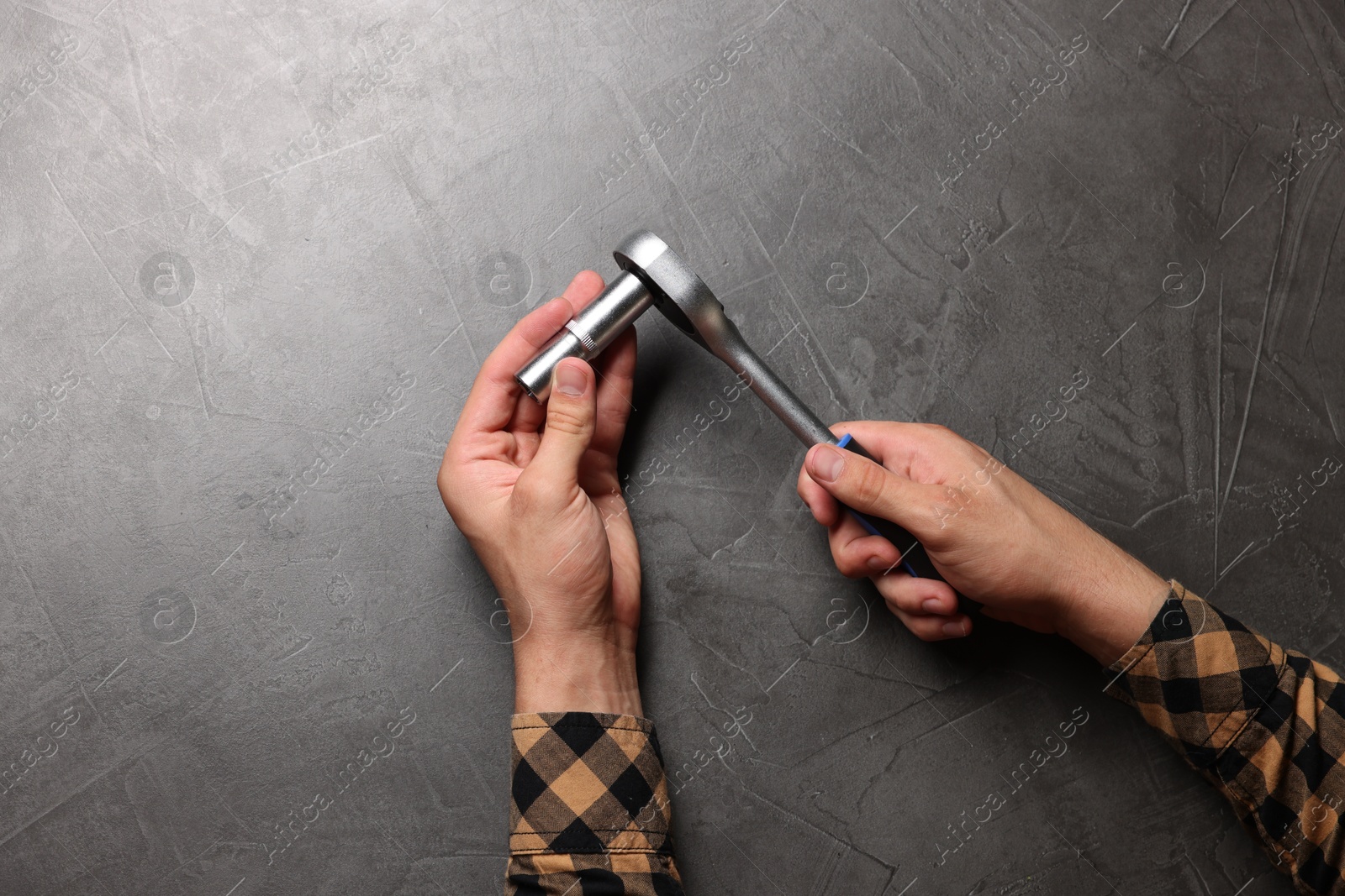 Photo of Auto mechanic with torque wrench at grey textured table, top view