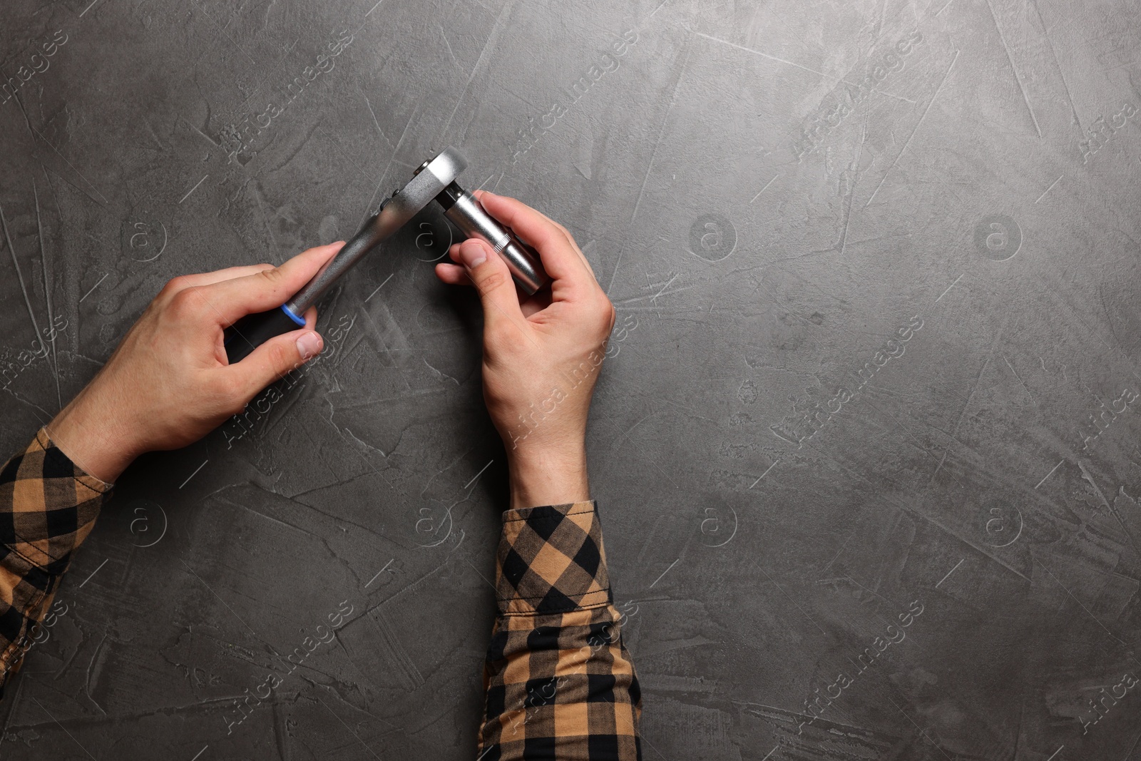 Photo of Auto mechanic with torque wrench at grey textured table, top view. Space for text