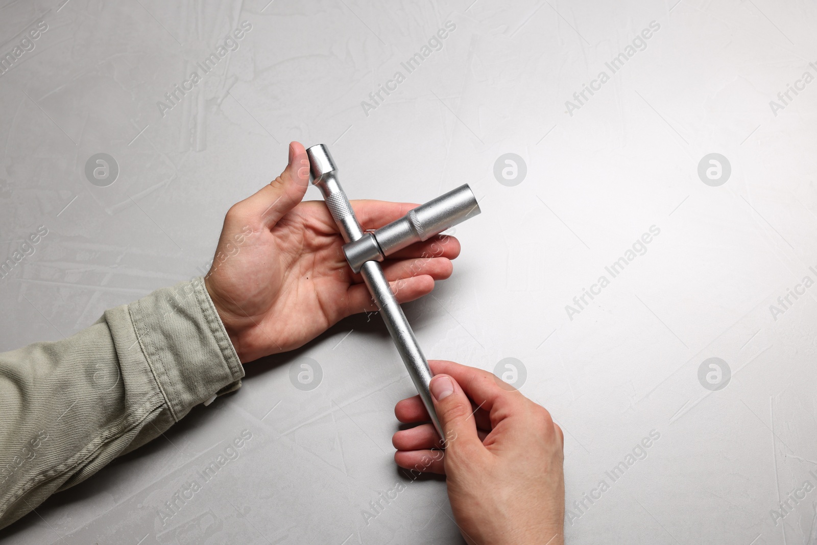 Photo of Auto mechanic with torque wrench at light grey textured table, closeup