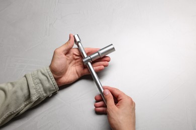 Auto mechanic with torque wrench at light grey textured table, closeup