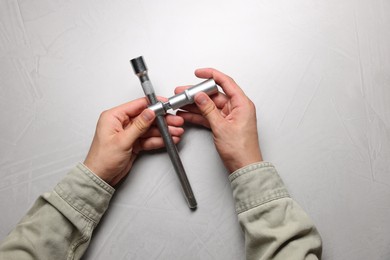 Photo of Auto mechanic with torque wrench at light grey textured table, top view