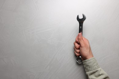 Photo of Auto mechanic with wrench at light grey textured table, top view. Space for text