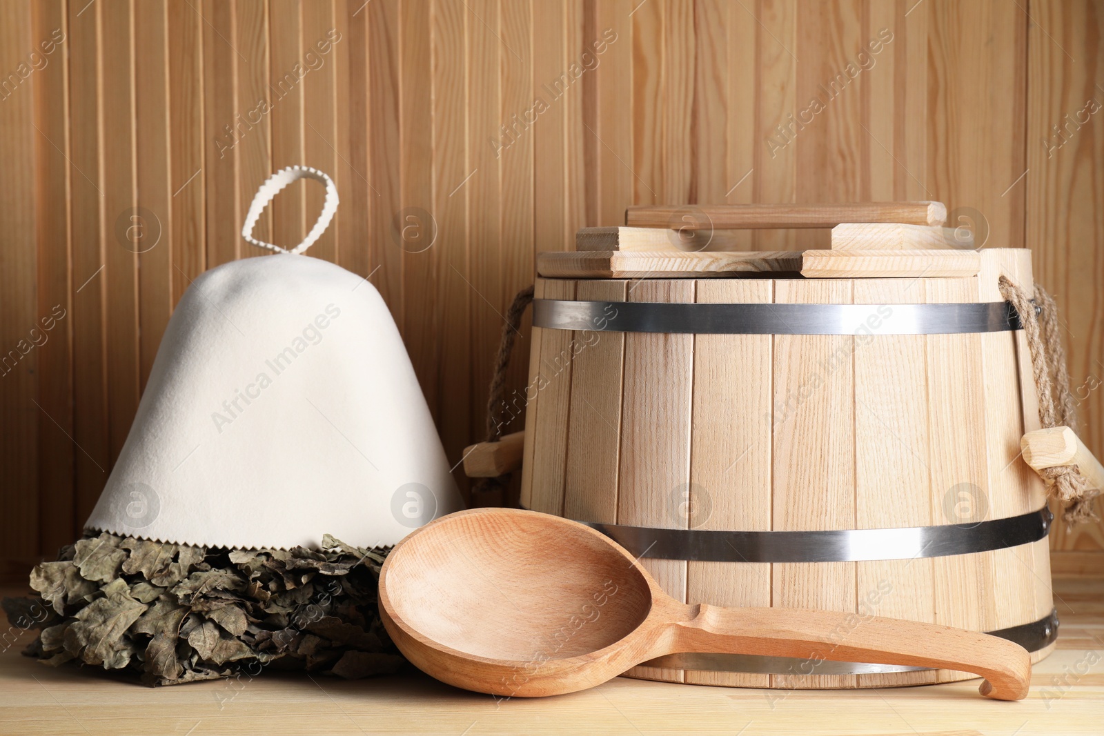 Photo of Oak sauna whisk, felt wool hat, bucket and ladle on wooden surface